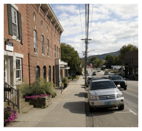 Cars parked along a downtown village street in summer. 