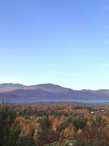 A sweeping view of mountains in fall with forests and leaves of vibrant colors.