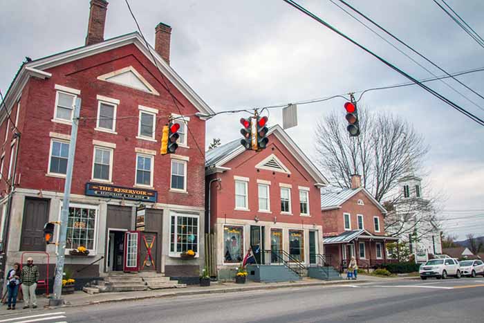 Brick buildings with restaurants and breweries at a village intersection . 