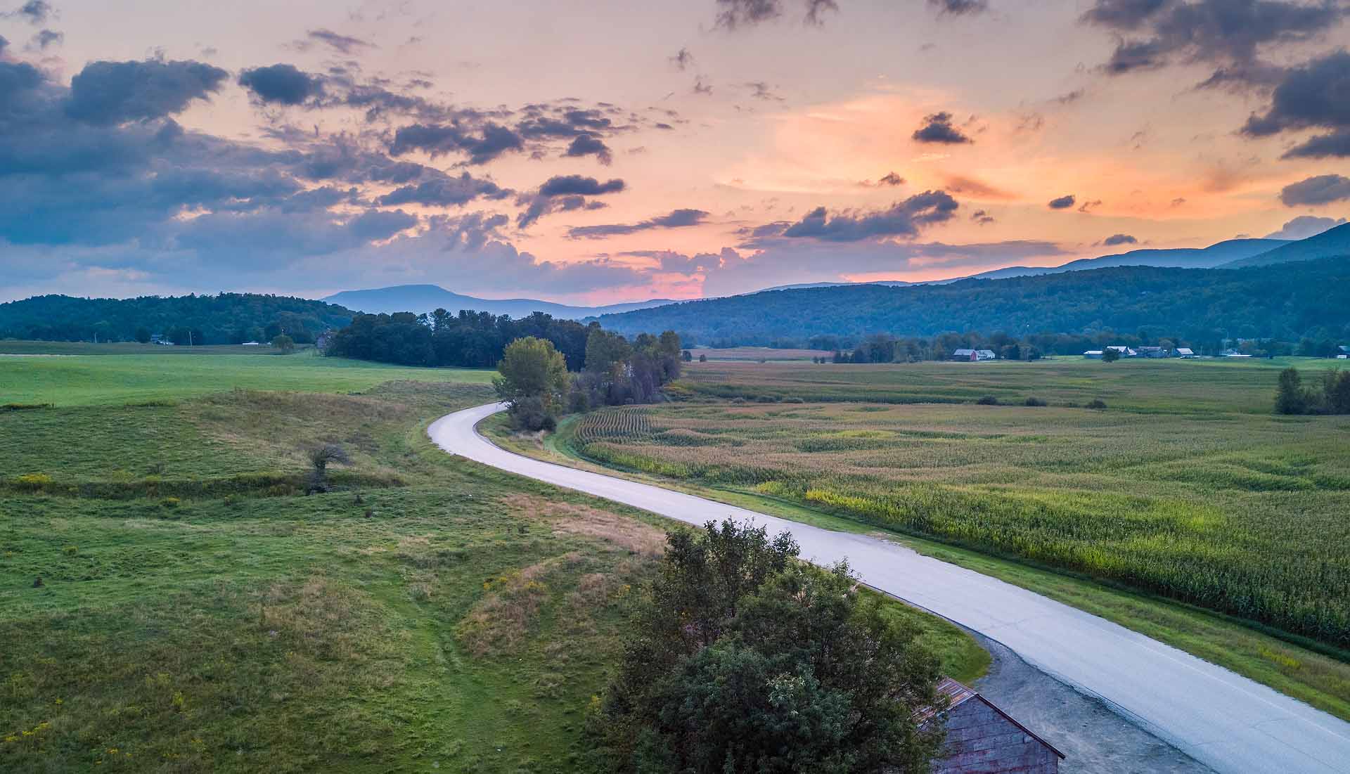 Fields and mountains in the distance along a winding road.