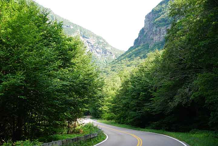 A paved road leads into the forest and toward the hills of Smugglers' Notch.