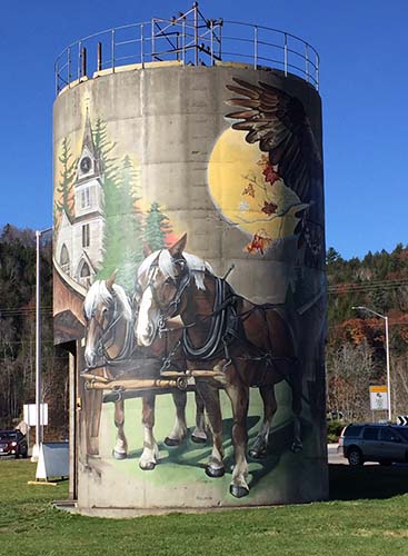 A painting of a team of horses with a church and a sun on a 36-foot silo.