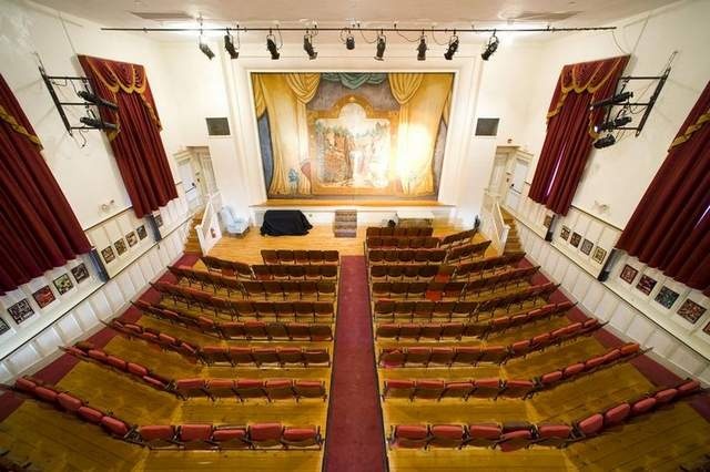 An historic village theater, with orchestra and balcony seating leading to the stage.