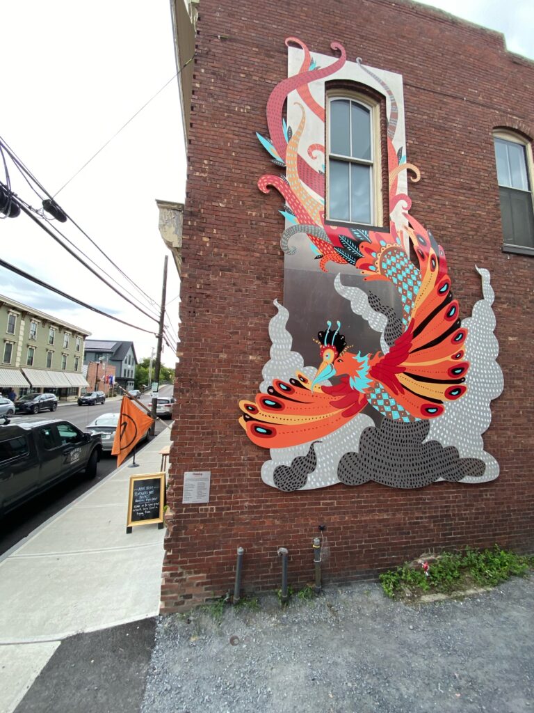 A mural of a Phoenix rising from flames on a brick corner building in Waterbury.